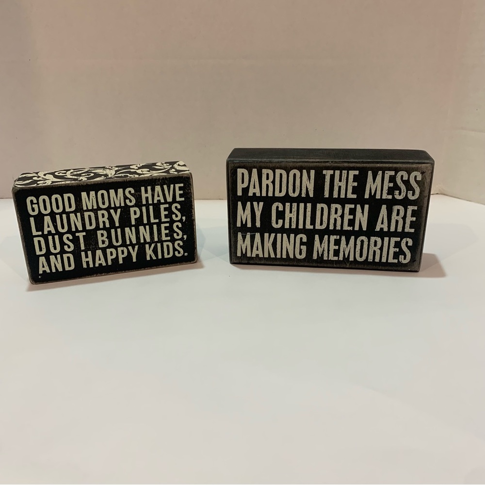 Primitives by Kathy mom focused wooden signs. Black signs with white writing.